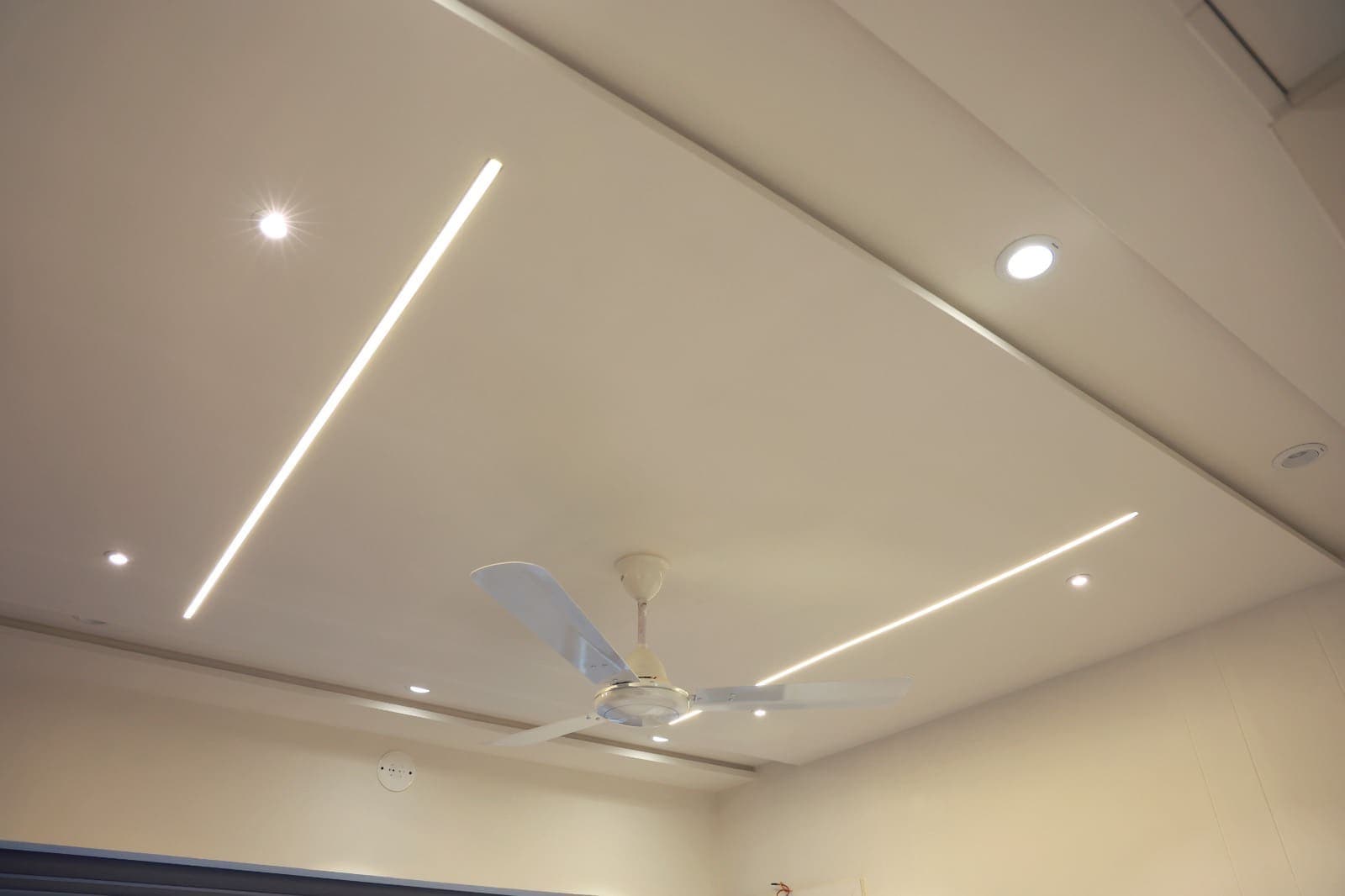 Ceiling with recessed linear light channels crossing at an angle